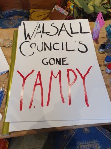 A partially painted placard reading "Walsall Council's gone Yampy"