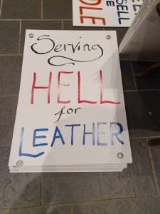 A partially painted placard reading "Serving Hell for Leather"