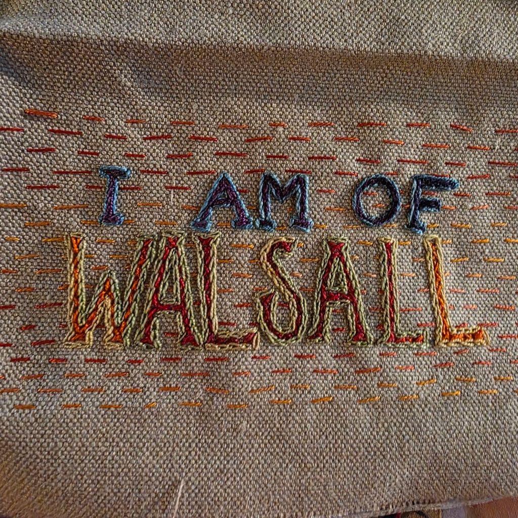 "I Am Of Walsall" embroidered in multicoloured thread on tabby weave linen