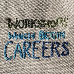 "Workshops which begin careers" embroidered in multicoloured thread on tabby weave linen