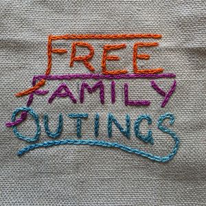 "Free Family Outings" embroidered in multicoloured thread on tabby weave linen