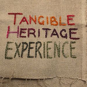 "Tangible Heritage Experience" embroidered in multicoloured thread on tabby weave linen